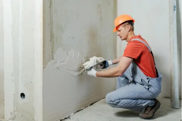 man installing white stucco on wall